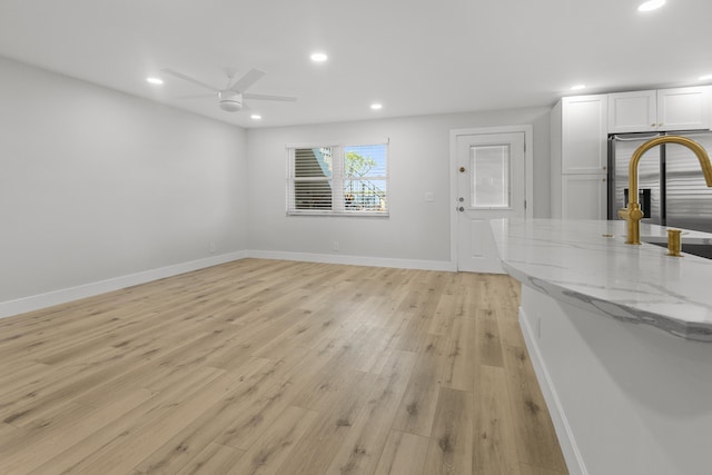 unfurnished living room with ceiling fan, a sink, light wood finished floors, recessed lighting, and baseboards
