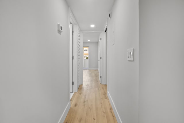 hallway featuring light wood-style floors, baseboards, and recessed lighting