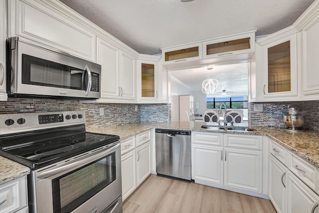 kitchen with a sink, backsplash, stainless steel appliances, and white cabinetry
