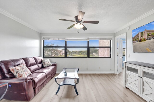 living area featuring crown molding, ceiling fan, a textured ceiling, light wood-style flooring, and baseboards