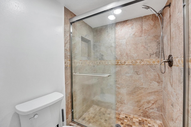 full bath featuring a shower stall and toilet