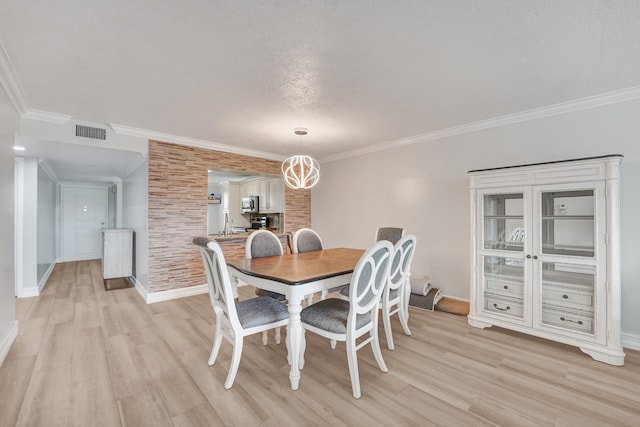 dining area with baseboards, visible vents, ornamental molding, and light wood-type flooring