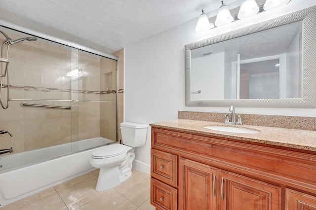 bathroom with shower / bath combination with glass door, tile patterned flooring, vanity, toilet, and baseboards
