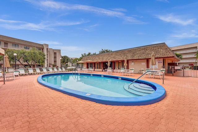 community pool with a patio and fence