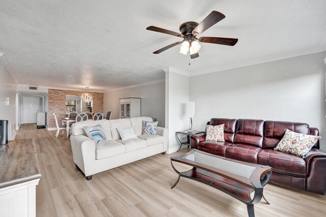 living room featuring crown molding, light wood finished floors, a ceiling fan, baseboards, and visible vents