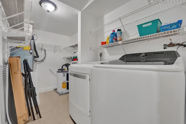 laundry room with light tile patterned flooring, laundry area, separate washer and dryer, water heater, and baseboards