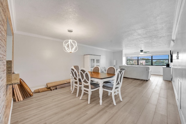 dining space featuring crown molding, light wood-style floors, a textured ceiling, ceiling fan with notable chandelier, and baseboards