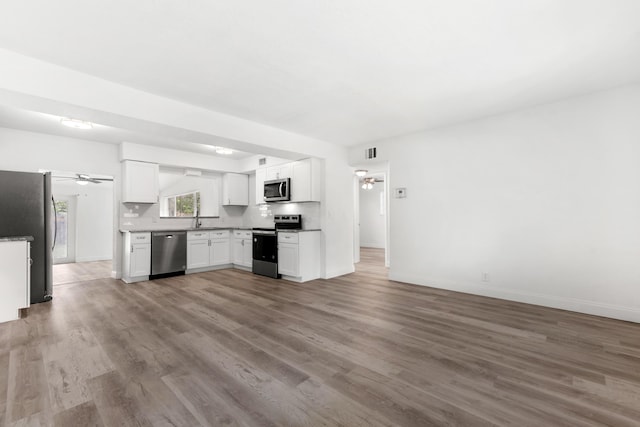 1134 NW 18th Ave, Fort Lauderdale, FL 33311 - kitchen featuring a ceiling fan, wood finished floors, open floor plan, stainless steel appliances, and white cabinets