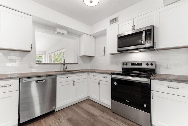 1134 NW 18th Ave, Fort Lauderdale, FL 33311 - kitchen with light wood-style flooring, stainless steel appliances, backsplash, a sink, and white cabinets