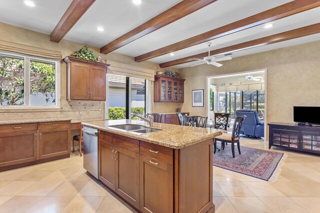kitchen with light stone counters, dishwasher, beamed ceiling, a center island with sink, and decorative backsplash