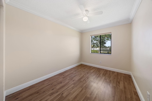 empty room with crown molding, baseboards, a textured ceiling, and wood finished floors