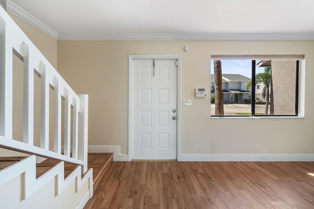 foyer entrance featuring ornamental molding, baseboards, stairway, and wood finished floors