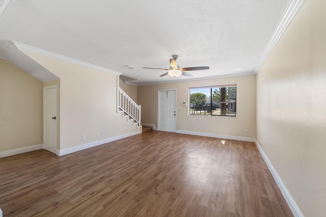 unfurnished living room with crown molding, stairway, baseboards, a ceiling fan, and wood finished floors