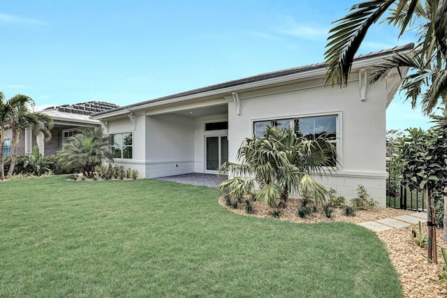 rear view of property featuring a lawn and stucco siding