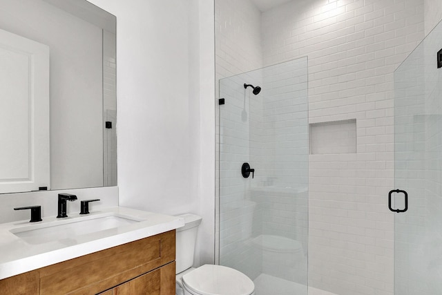 full bathroom featuring vanity, a stall shower, and toilet