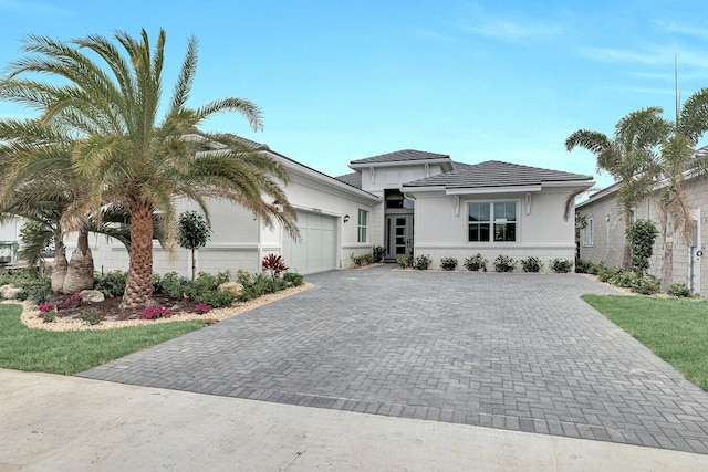 view of front of property with an attached garage, stucco siding, and decorative driveway