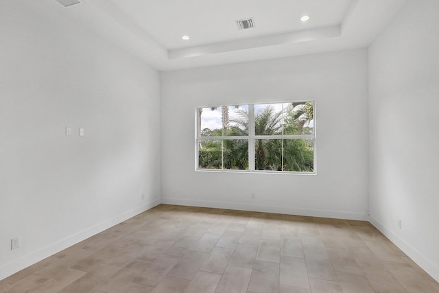 spare room with a raised ceiling, baseboards, recessed lighting, and visible vents