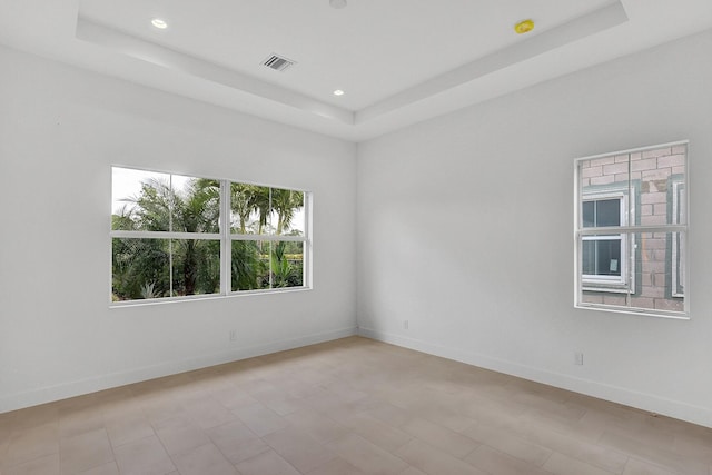 spare room featuring recessed lighting, a raised ceiling, and baseboards