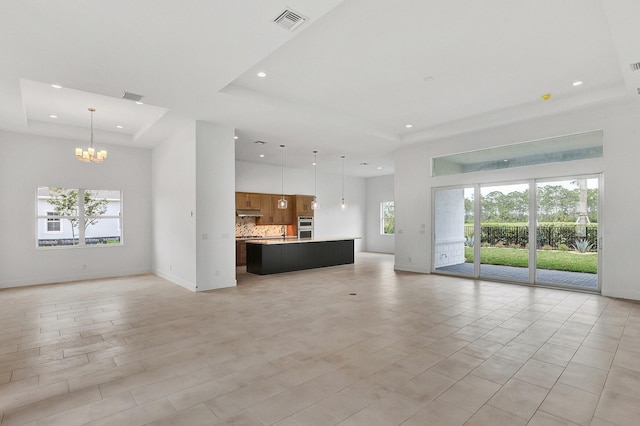 unfurnished living room featuring recessed lighting, visible vents, an inviting chandelier, and a raised ceiling