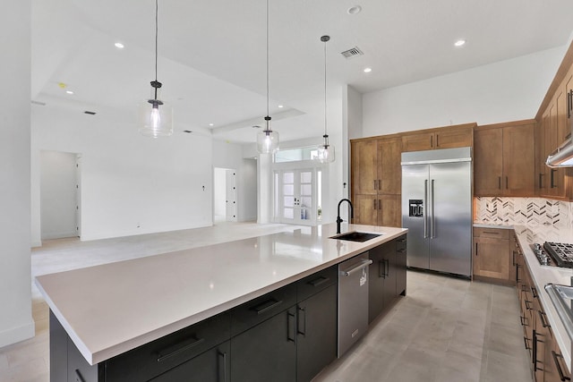 kitchen with visible vents, a large island with sink, a sink, backsplash, and stainless steel appliances