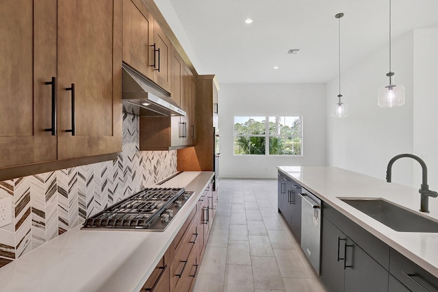 kitchen featuring light countertops, under cabinet range hood, tasteful backsplash, a sink, and stainless steel appliances
