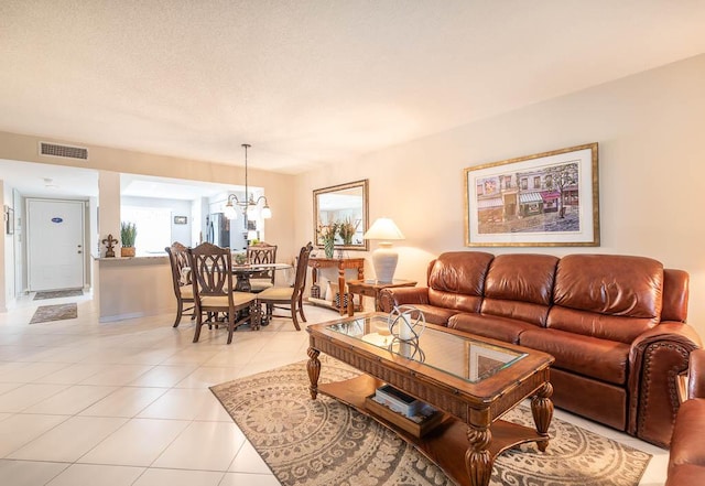 living area featuring light tile patterned floors, a notable chandelier, a textured ceiling, and visible vents