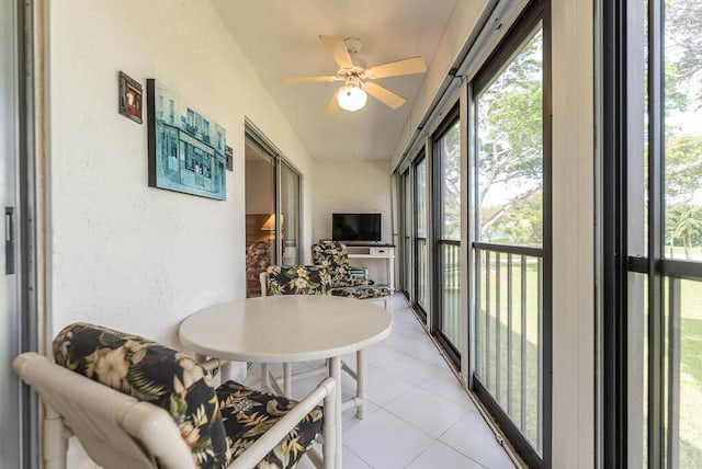 sunroom / solarium featuring a textured wall, tile patterned flooring, and a ceiling fan