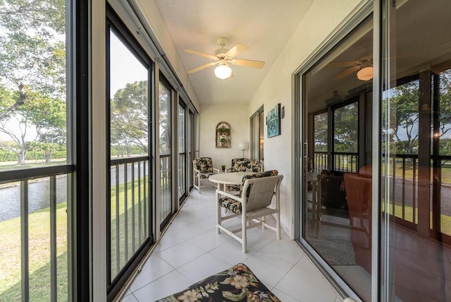 sunroom / solarium with a ceiling fan, a water view, and tile patterned flooring