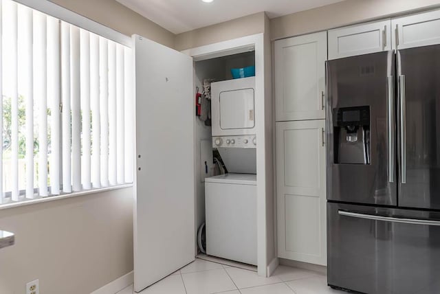 laundry room featuring stacked washer and clothes dryer, laundry area, and light tile patterned flooring