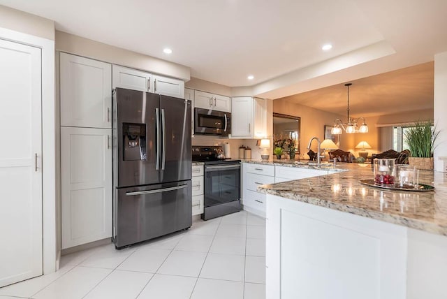 kitchen featuring a peninsula, light stone countertops, appliances with stainless steel finishes, a sink, and pendant lighting