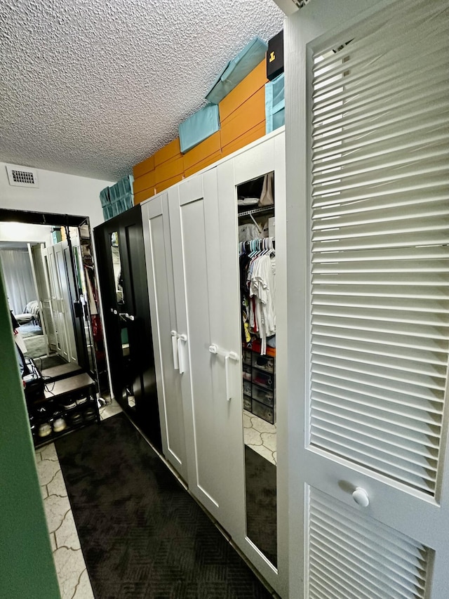 hallway featuring a textured ceiling and visible vents
