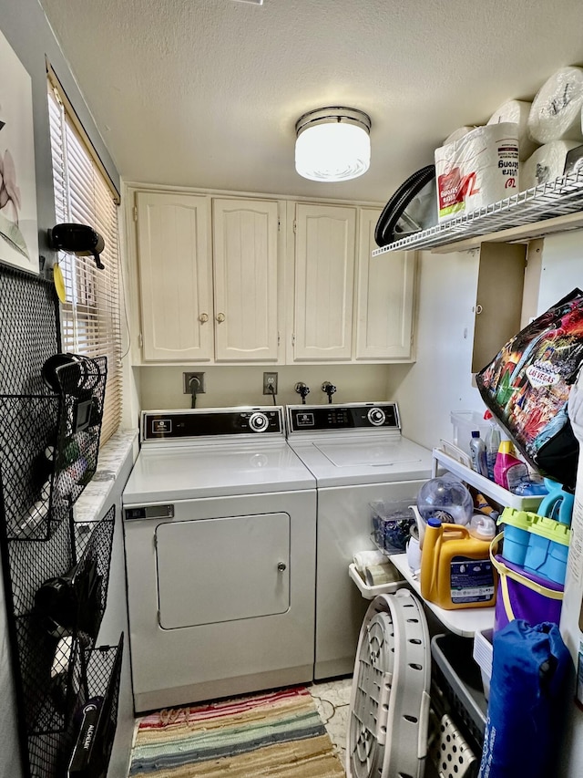 washroom featuring a textured ceiling, cabinet space, and washing machine and dryer