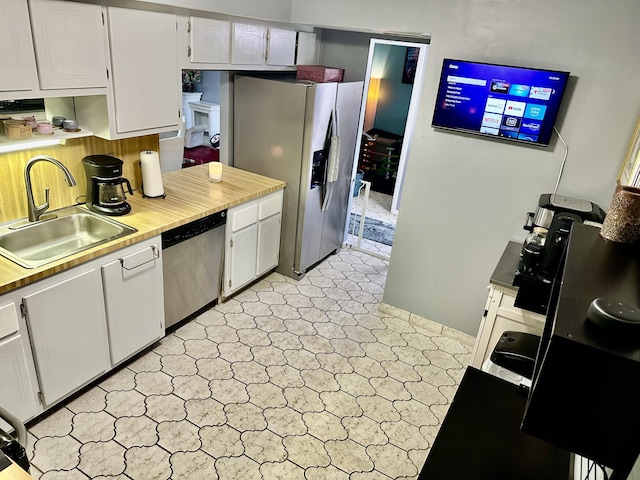 kitchen with stainless steel appliances, white cabinets, light countertops, and a sink