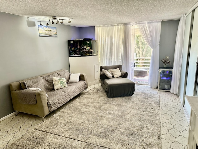 living area featuring baseboards, rail lighting, beverage cooler, and a textured ceiling