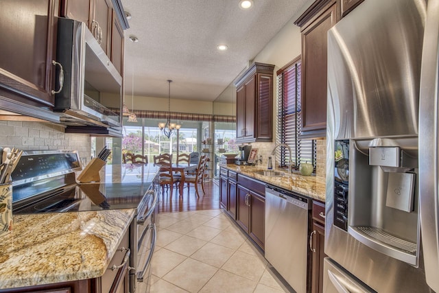 2036 SW Mayflower Dr, Palm City, FL 34990 - kitchen with appliances with stainless steel finishes, a sink, a textured ceiling, a chandelier, and light stone counters