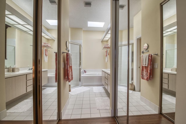 2036 SW Mayflower Dr, Palm City, FL 34990 - full bathroom featuring a skylight, vanity, a stall shower, a garden tub, and a textured ceiling