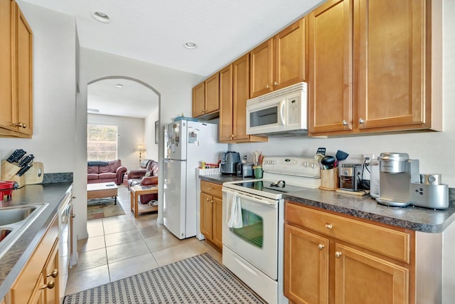 2061 SE Glen Ridge Dr, Port Saint Lucie, FL 34952 - kitchen with dark countertops, a sink, white appliances, light tile patterned floors, and arched walkways