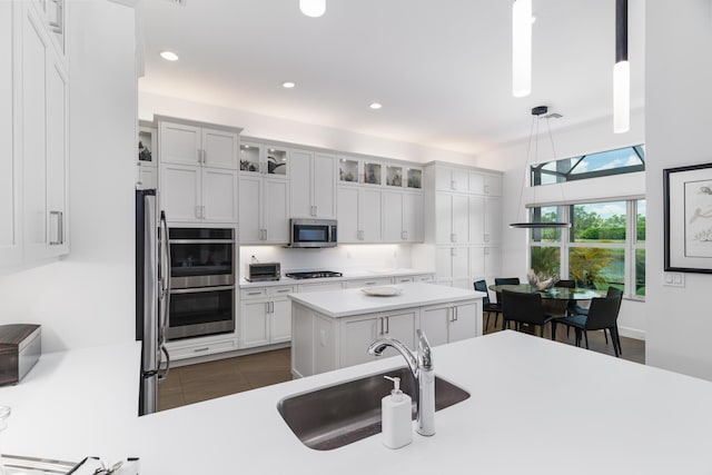 9237 Seahorse Bay Dr, Boynton Beach, FL 33473 - kitchen with light countertops, appliances with stainless steel finishes, glass insert cabinets, a sink, and decorative light fixtures