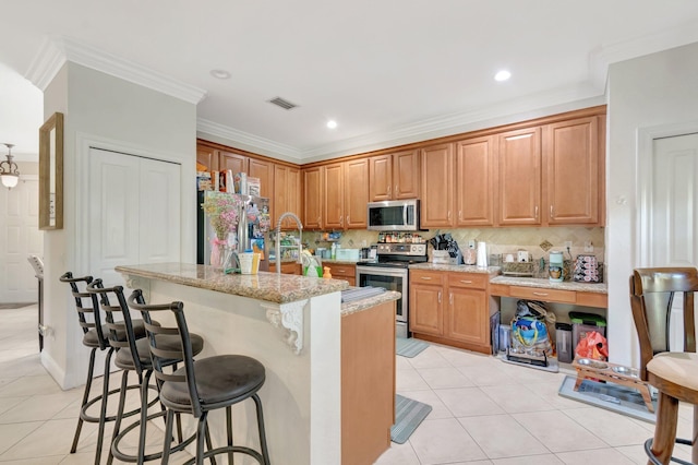 5541 Wishing Star Ln, Greenacres, FL 33463 - kitchen featuring visible vents, a kitchen island with sink, ornamental molding, appliances with stainless steel finishes, and light tile patterned floors