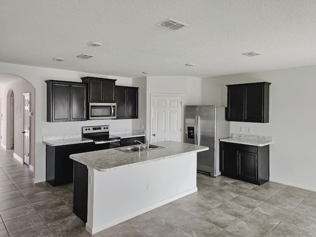 9213 Potomac Dr, Fort Pierce, FL 34945 - kitchen featuring dark cabinetry, stainless steel appliances, a sink, arched walkways, and visible vents