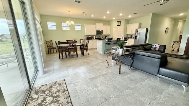 living room featuring light tile patterned floors, visible vents, recessed lighting, and ceiling fan with notable chandelier