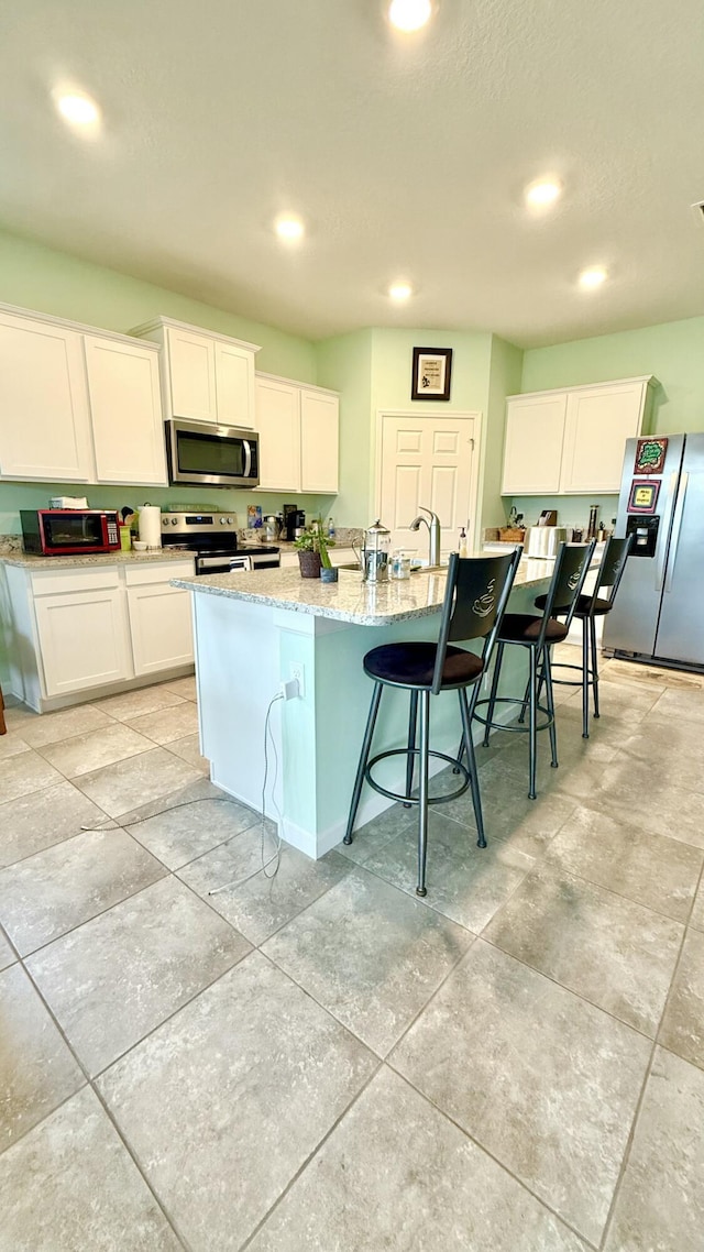 kitchen featuring white cabinets, light stone countertops, stainless steel appliances, and recessed lighting
