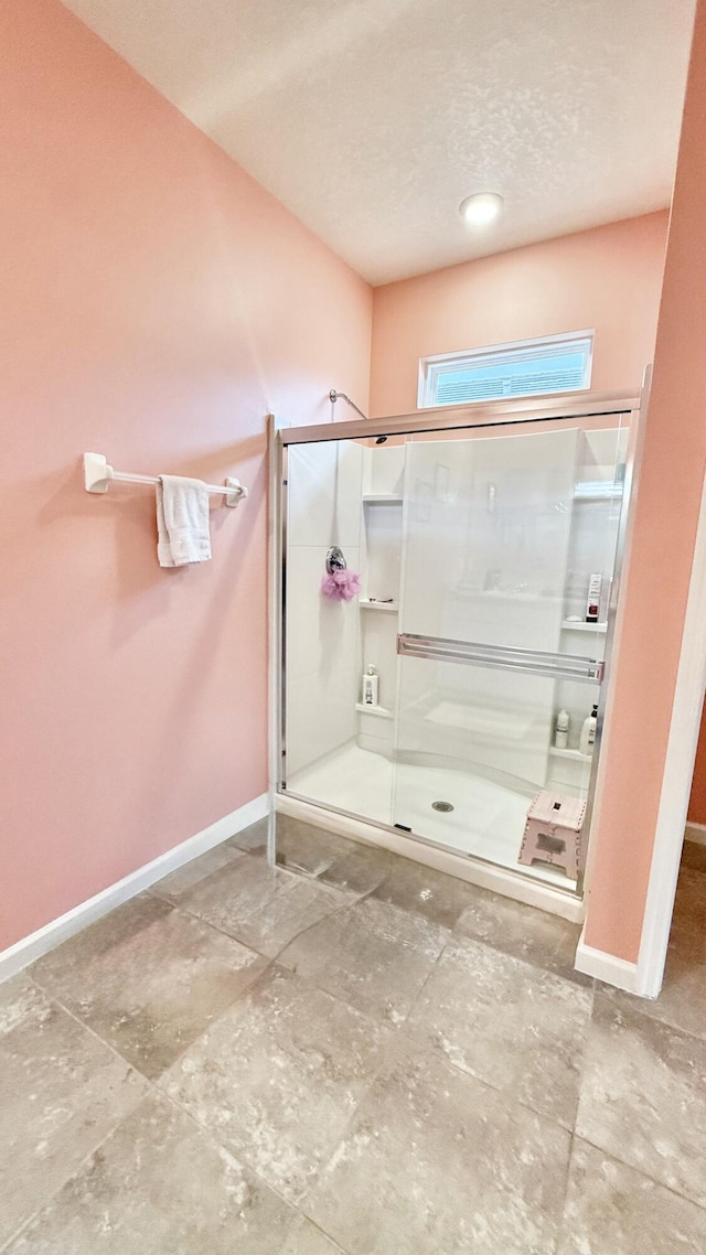 full bathroom with baseboards, a textured ceiling, and a stall shower