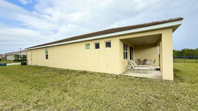 back of house with a lawn, stucco siding, fence, and a patio area
