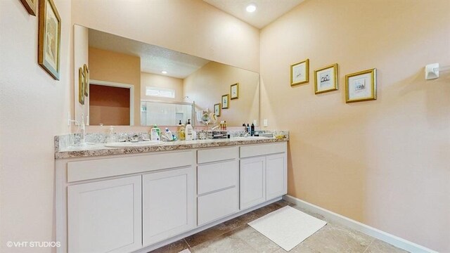 10577 SW Toren Way, Port Saint Lucie, FL 34987 - bathroom featuring a shower stall, double vanity, and baseboards