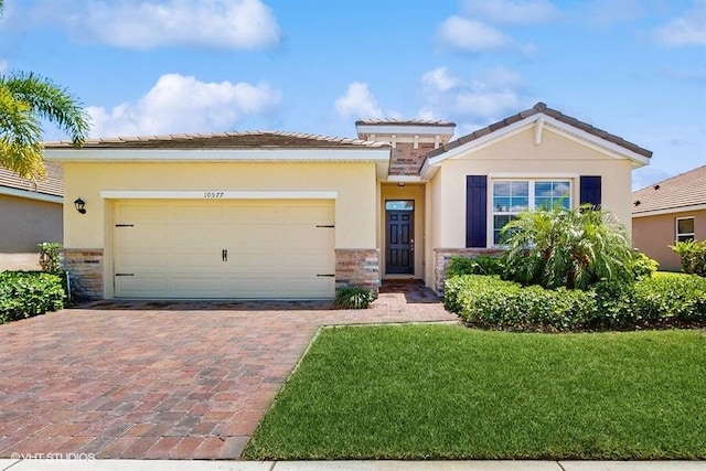 10577 SW Toren Way, Port Saint Lucie, FL 34987 - view of front of property featuring stone siding, stucco siding, a garage, driveway, and a front yard