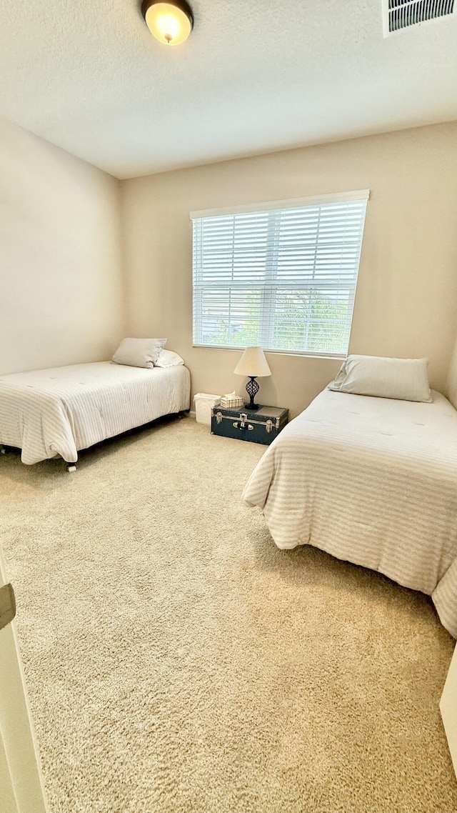 carpeted bedroom with a textured ceiling and visible vents