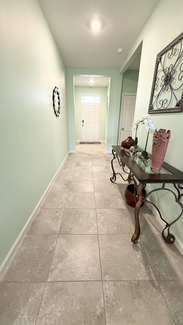 hallway with tile patterned floors and baseboards