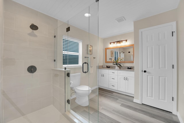 1701 SE Floresta Dr, Port Saint Lucie, FL 34983 - bathroom featuring double vanity, a stall shower, toilet, wood finished floors, and baseboards