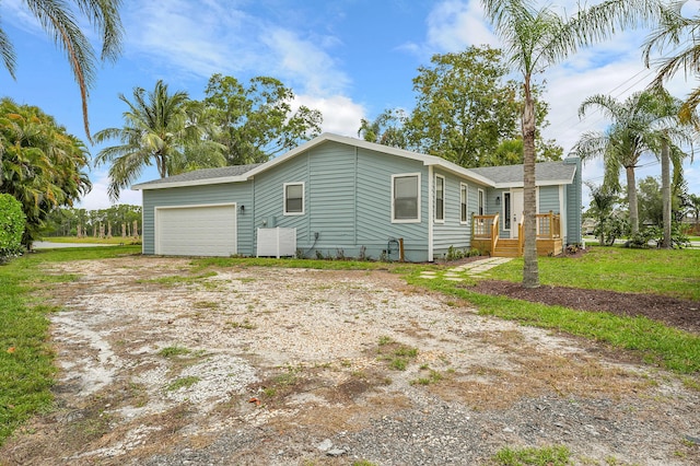 1701 SE Floresta Dr, Port Saint Lucie, FL 34983 - view of home's exterior featuring dirt driveway, a wooden deck, a garage, and a shingled roof